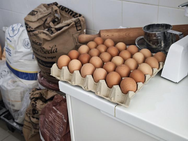  Imagen en la que se pueden ver utensilios de la repostería artesanal, huevos, sacos de harina y otras materias primas.
